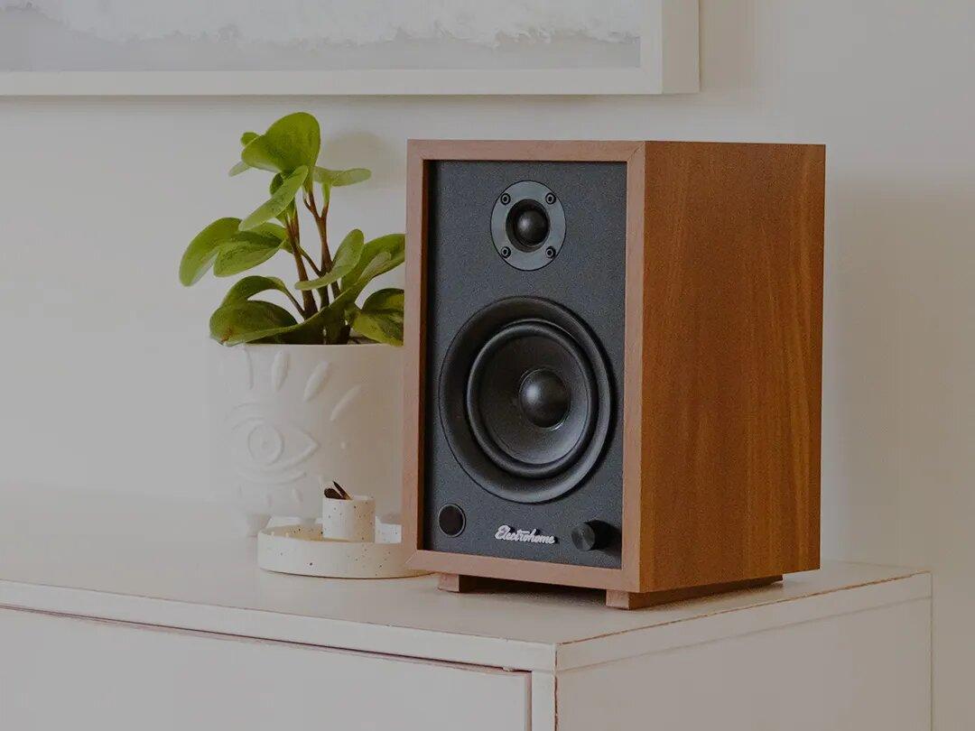 Electrohome Huntley Powered Bookshelf Speakers placed on a shelf with plant pot